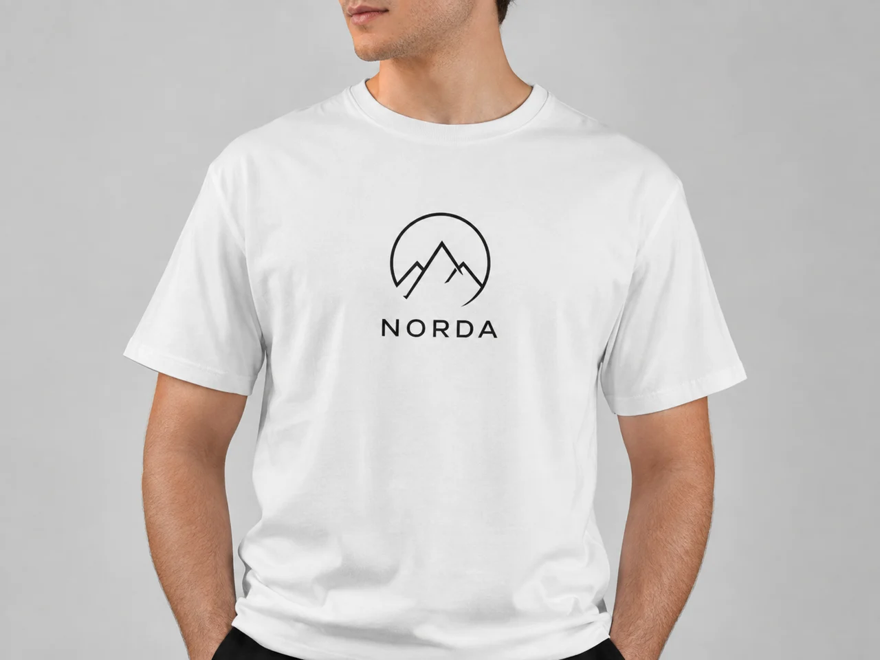 Логотип NORDA на белой хлопковой футболке на человеке: печать повторяет складки ткани, фон светло-серый